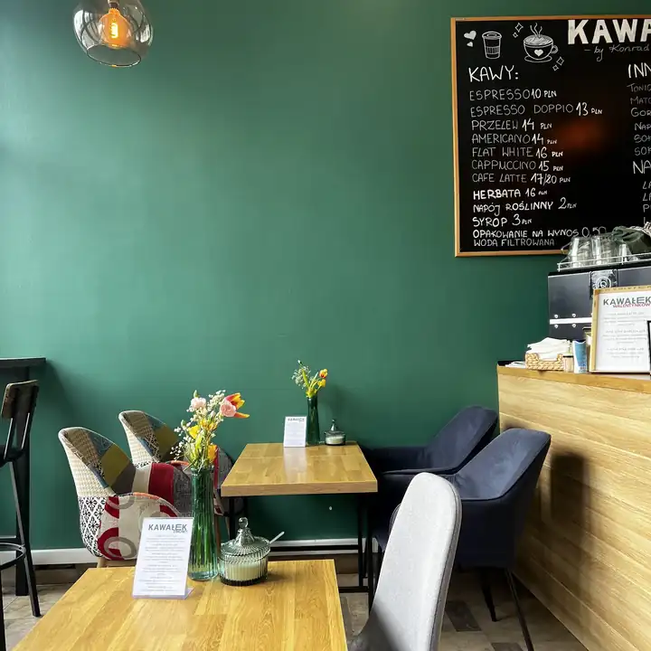 Bar z tablicą kaw i stoliki pod zieloną ścianą